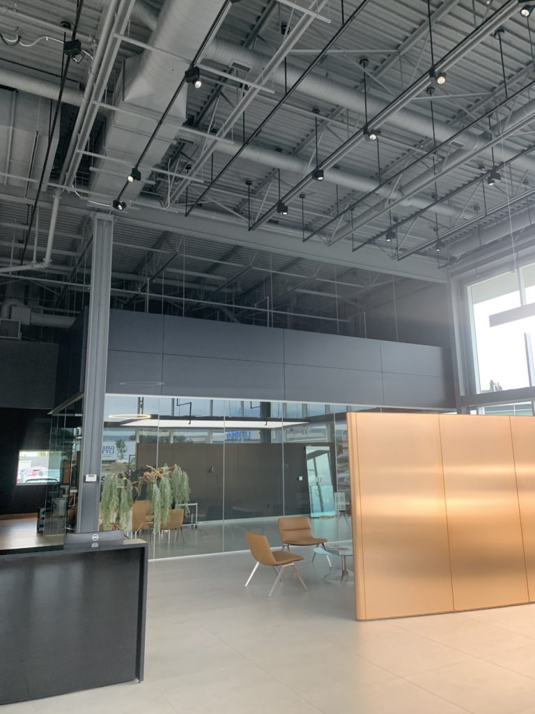 Poplar Painting - Modern office lobby with high ceiling, exposed ductwork, and a mix of natural and artificial lighting, featuring minimalistic furniture and a muted color scheme.