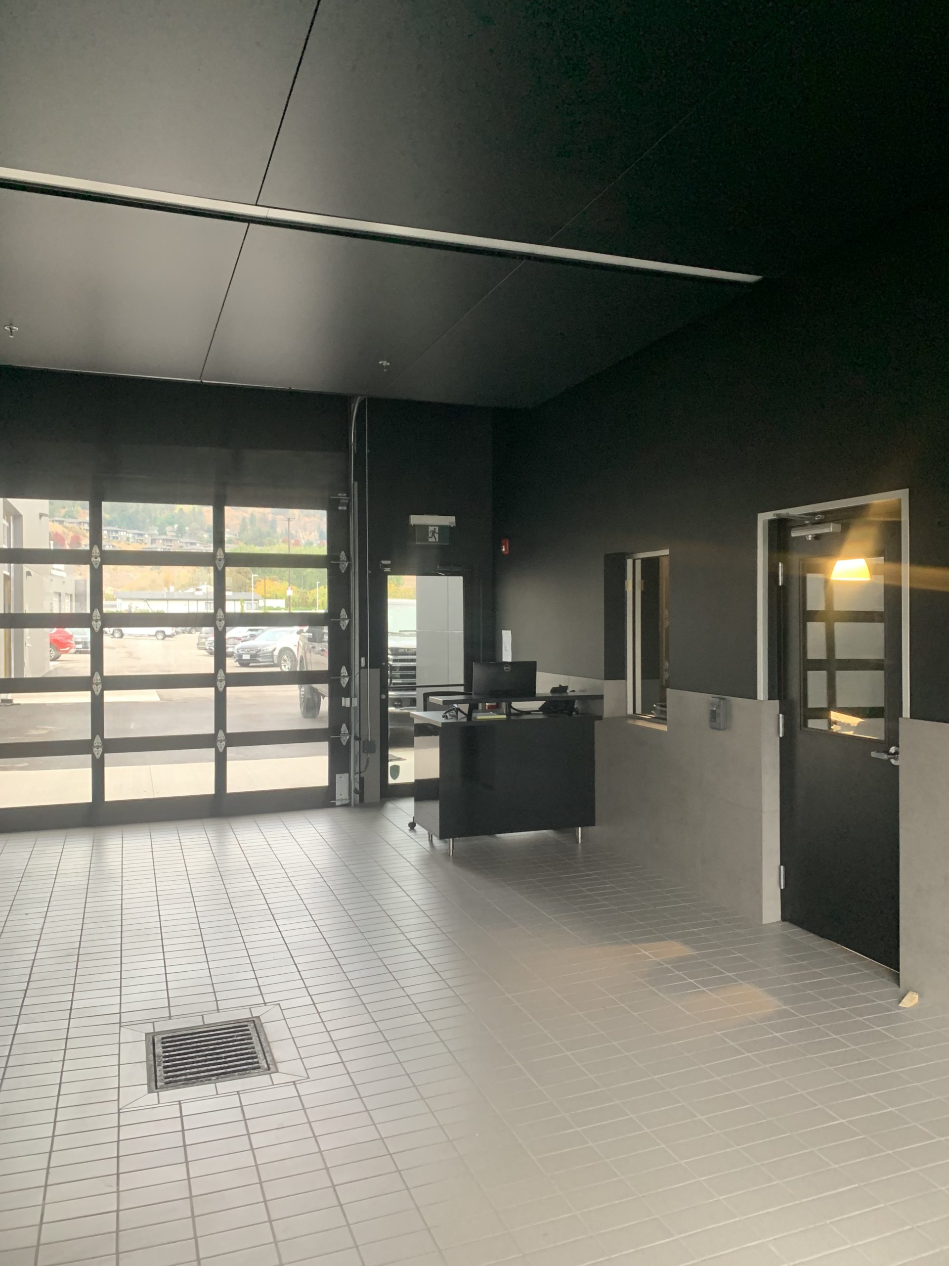 Poplar Painting - Modern office lobby with minimalist black decor, natural light entering through glass doors, and a reception desk to the right.